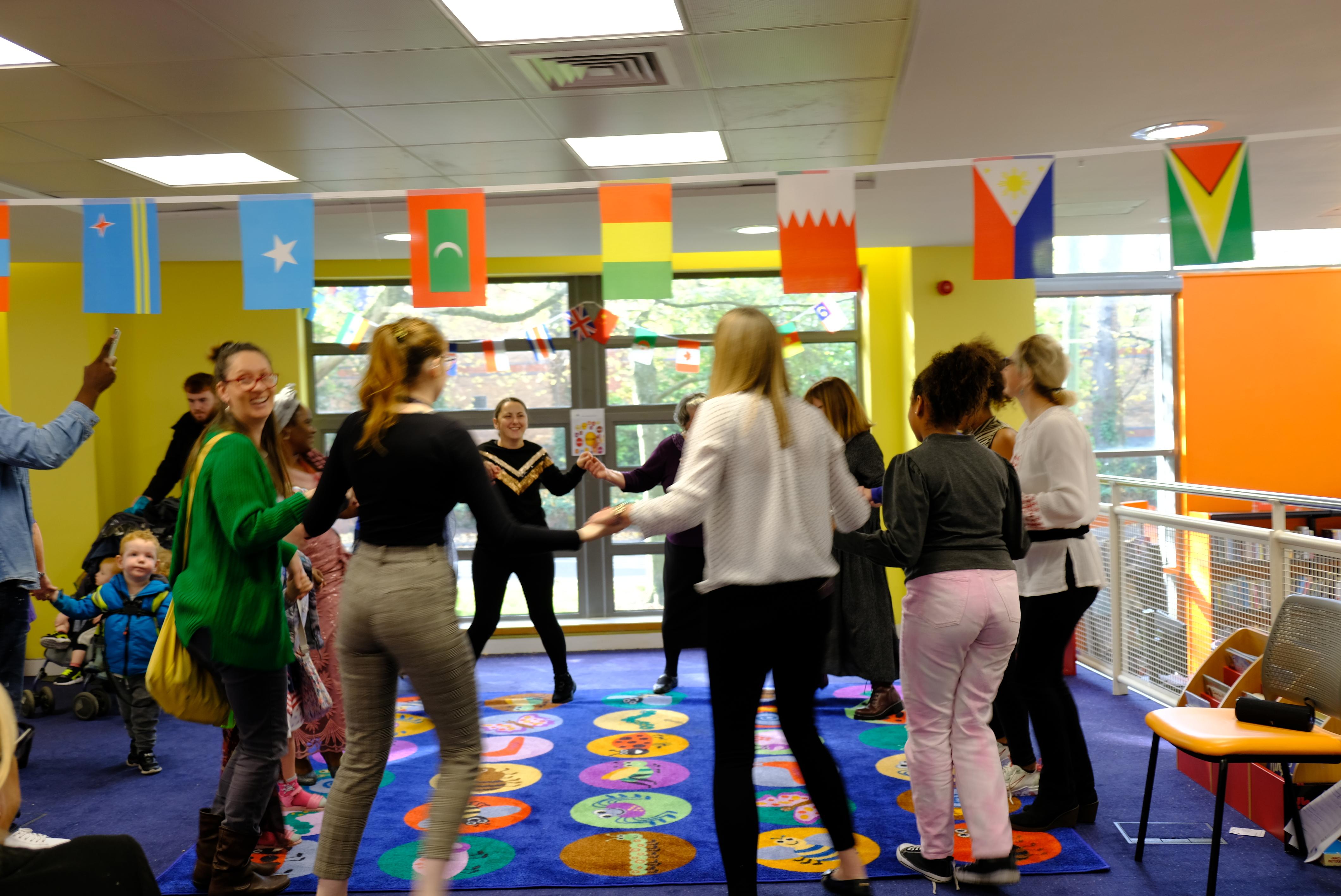 Image of EAL event, families dancing with flags above them of countries from all around the world. 